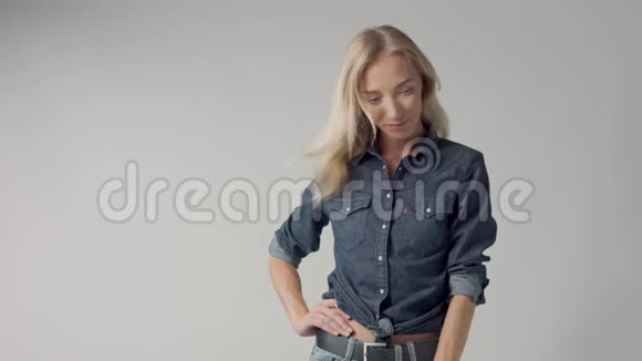 摄影棚里年轻的金发美女穿着经典的牛仔布吹毛求疵视频的预览图