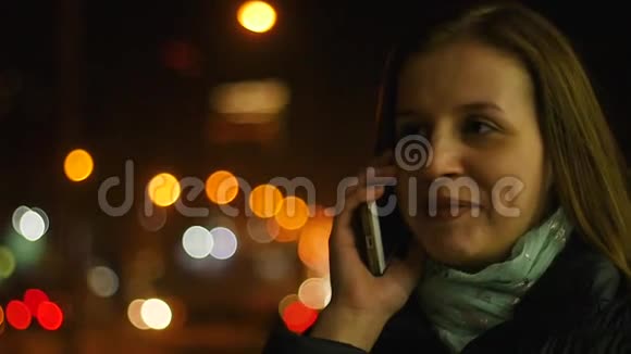美丽的年轻女子在智能手机上交谈穿过夜城视频的预览图