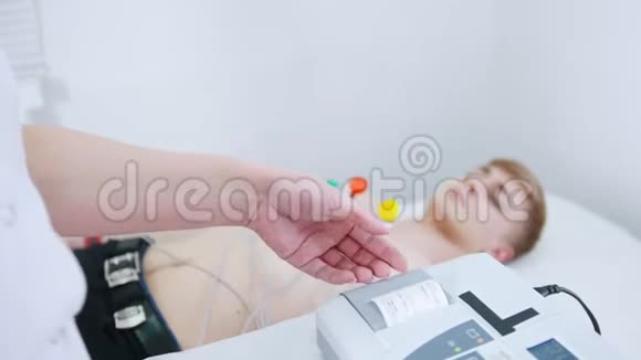一家医疗诊所接受心电图检查的年轻人从机器里出来的结果磁带视频的预览图