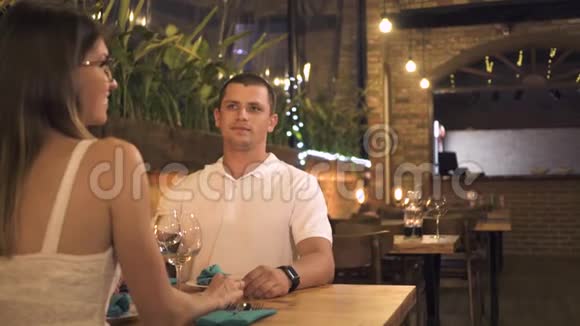 一对浪漫的夫妇坐在晚餐桌前的晚餐餐厅男人和女人在浪漫晚餐时和女服务员交谈视频的预览图