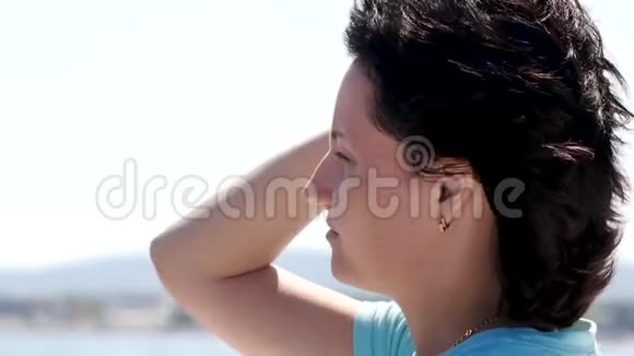 一个年轻女人的脸那个女孩摸着她在风中飘扬的头发夏天在游艇上的女孩视频的预览图