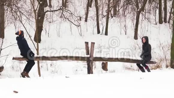 慢动作一对夫妇在雪地森林里骑着自制的秋千视频的预览图