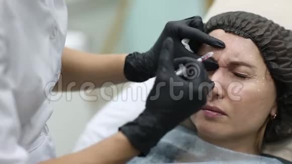 美容医生给她的女客户做面部美容注射美丽的女性面容和美容师双手视频的预览图
