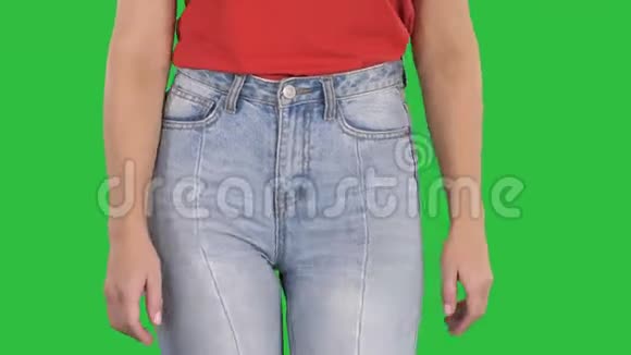 休闲女性穿着高牛仔裤和红色t恤走在绿色屏幕上铬钥匙视频的预览图