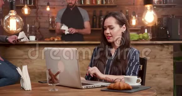 漂亮深褐色头发的女人在电脑上工作时接电话视频的预览图
