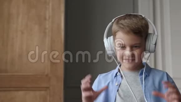 快乐的孩子听音乐美丽的微笑男孩戴耳机视频的预览图