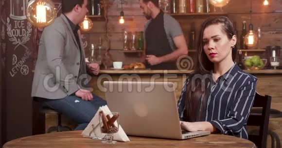 年轻漂亮的女人在她的笔记本电脑上工作服务员端咖啡视频的预览图