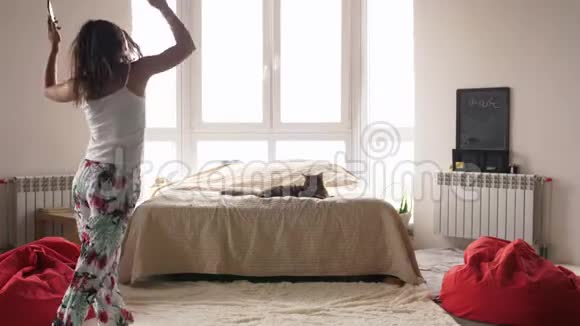 快乐的年轻女子穿着睡衣在家跳舞带着耳机听音乐享受周末的快乐视频的预览图