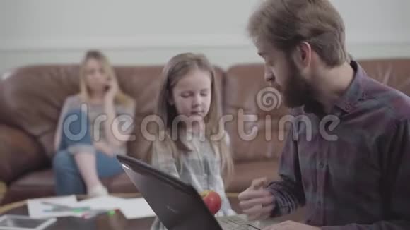 有胡子的人用笔记本电脑近距离工作的肖像小女孩试图给男人苹果但没有成功视频的预览图