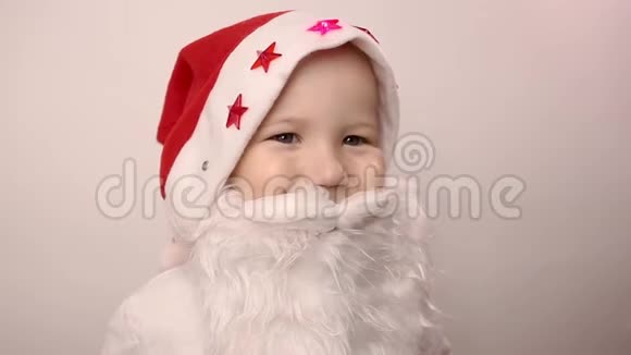 戴着圣诞老人帽子的假胡子的男孩微笑着在白色背景下笑视频的预览图
