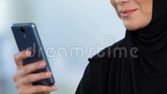 微笑阿拉伯妇女在手机上阅读信息在线聊天科技视频的预览图