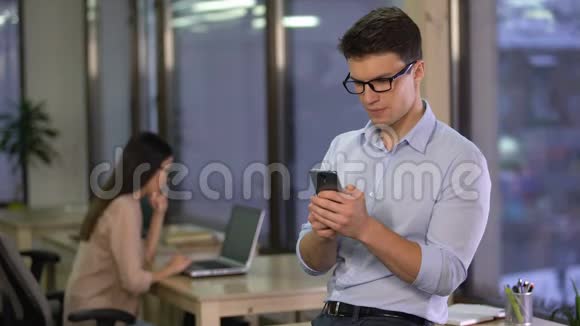 年轻人在办公室时在智能手机上使用智能家居应用程序现代技术视频的预览图