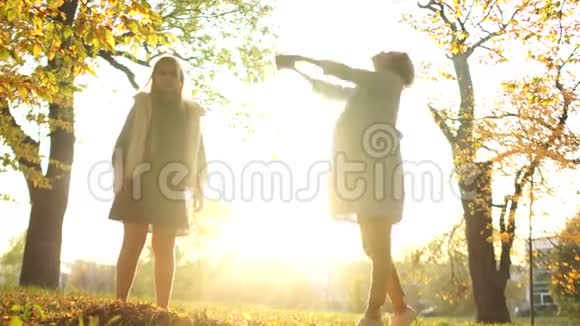 快乐的女人和一个女孩在秋天公园的背景下享受夕阳阳光灿烂母亲节视频的预览图