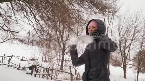 特写镜头胡德中的欢乐女孩在森林中投掷雪球视频的预览图