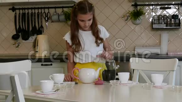 一个女孩从厨房的桌子上清洗一罐茶视频的预览图