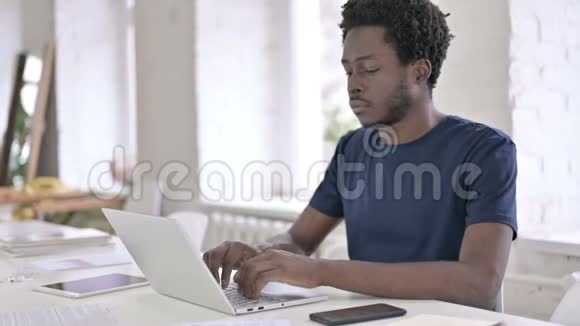 年轻的非洲设计师思考和工作笔记本电脑视频的预览图