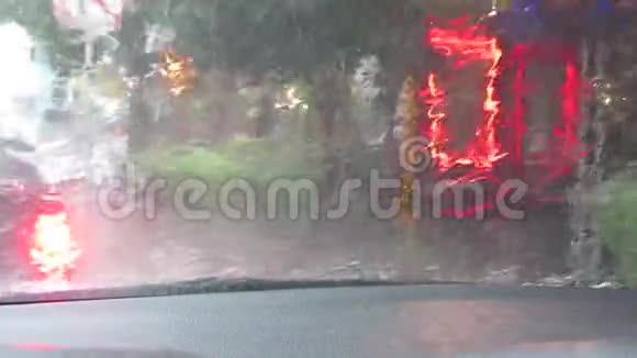 观市街在一场雷雨和大雨中穿过汽车的挡风玻璃模糊的广告灯视频的预览图