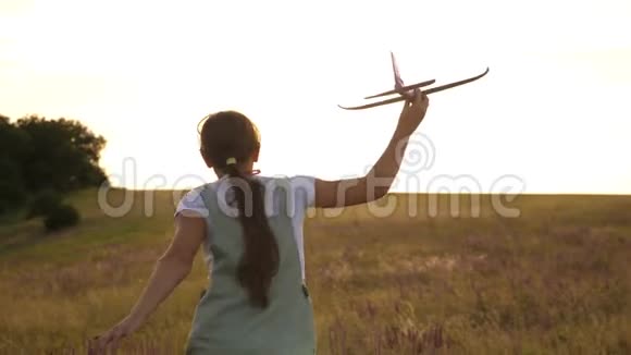 年轻女孩带着一架玩具飞机在田野上奔跑在阳光下孩子们玩玩具飞机少年梦想视频的预览图
