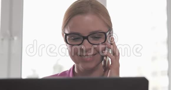 金发美女戴着眼镜在电话里看着摄像机视频的预览图