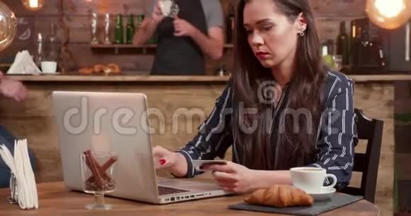 美丽的女人在网上购物时在笔记本电脑上介绍她的卡号视频的预览图