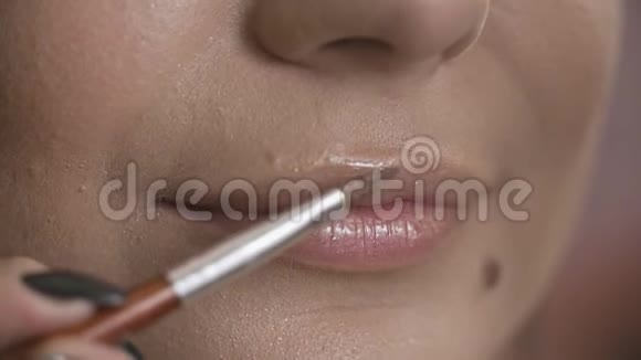 专业化妆师在模特的嘴唇上涂口红近景视频的预览图