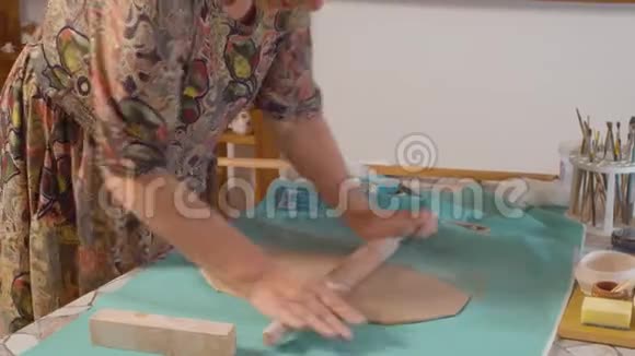 年长的女人把粘土卷成面团视频的预览图