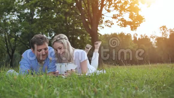一个男人和一个女孩正在看一张家庭相册里面有草地上公园里的照片视频的预览图