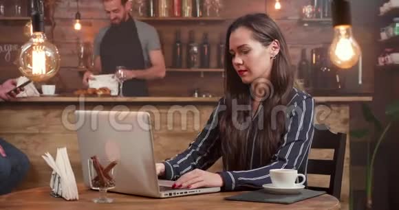 年轻有创造力的女人合上手提电脑离开一家小咖啡店的桌子视频的预览图