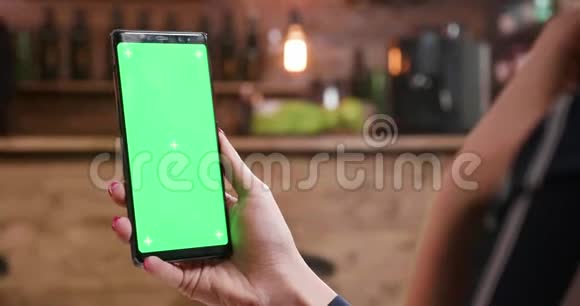 一位女士在显示绿色屏幕时专注于她的智能手机视频的预览图