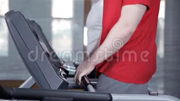 男人在健身房的跑步机上慢慢行走视频的预览图