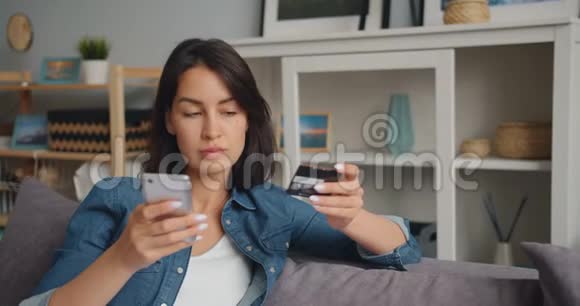 使用智能手机用银行卡在线支付快乐女人的慢动作视频的预览图