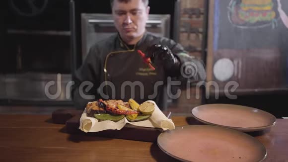 专业厨师穿着特别黑色制服供应一盘三文鱼烤鱼和烤蔬菜视频的预览图