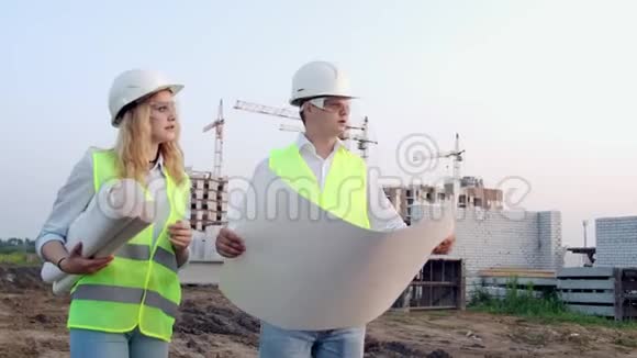 施工现场有图纸的工人两名工人一名男子一名妇女在保护性的哈达工作在视频的预览图