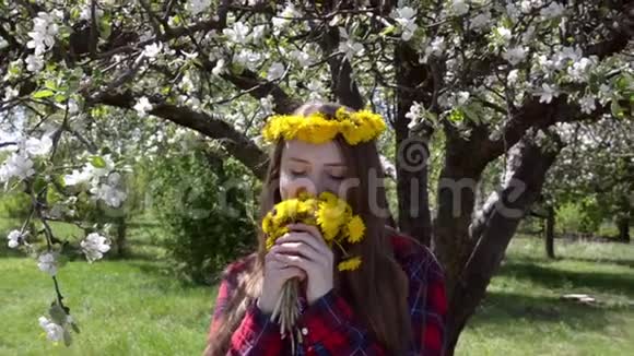 女孩头上戴着一束蒲公英和一个花环享受着气味视频的预览图