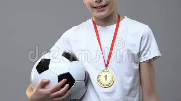 带着足球的男孩在灰色背景下站着第一块奖牌视频的预览图
