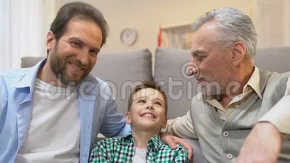 爸爸和爷爷拥抱男孩看着镜头家庭时间在家视频的预览图
