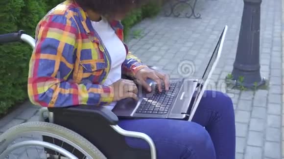 有非洲发型的非裔美国妇女轮椅残疾使用笔记本电脑太阳灯视频的预览图