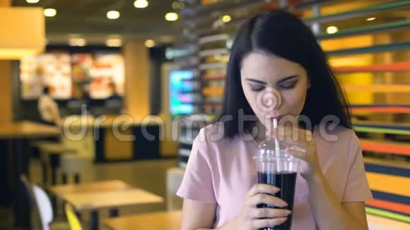 迷人的年轻女人从塑料杯中喝果汁微笑着喝软饮料视频的预览图