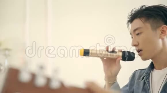 年轻的亚洲男歌手用吉他伴奏排练视频的预览图