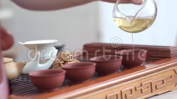 女人手轻轻地从一个玻璃茶壶里倒入四杯香茶视频的预览图