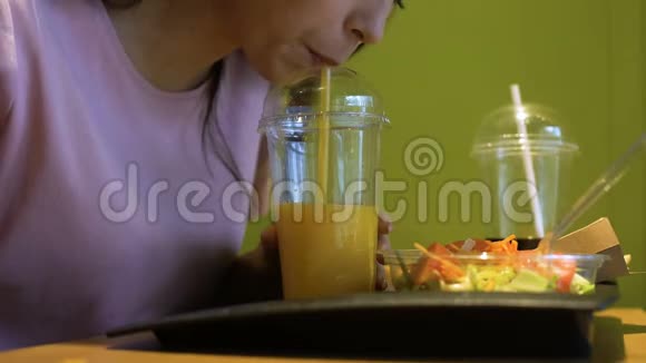 从塑料杯中通过吸管喝新鲜橙汁视频的预览图