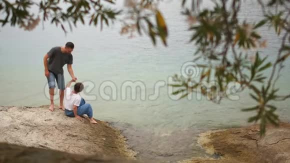 男人和女人正在一个陌生岛屿的岩石海岸上的一个僻静的角落里休息然后起身离开视频的预览图