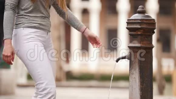 一个年轻的女人从街道喷泉里喝水视频的预览图