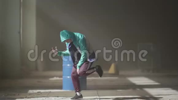 经验丰富的年轻嘻哈舞蹈家在雾中的一座废弃的建筑里靠近木桶跳舞嘻哈文化排练视频的预览图