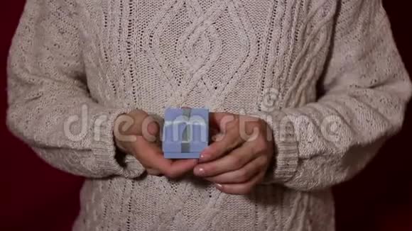 漂亮的女孩在一个蓝色的小盒子里扭着手里的礼物美丽的女性手拿着一个带礼物的蓝色小盒子摇一摇视频的预览图