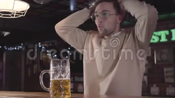 英俊的大胡子男人开心地笑着在酒吧喝啤酒看电视上的足球比赛它的风扇视频的预览图