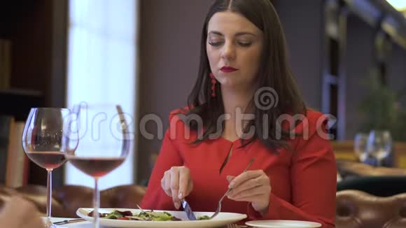 红衣女人坐在餐厅吃美味的沙拉视频的预览图