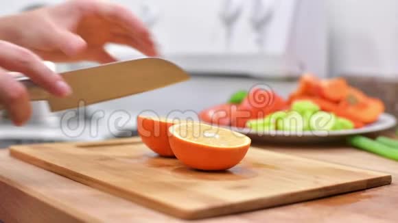 女人用菜刀在木板上切新鲜的橘子视频的预览图
