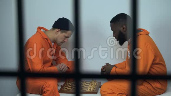 白种人和非洲裔美国监狱囚犯在牢房里下棋在监狱里的爱好视频的预览图