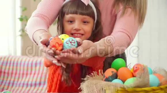 一幅欢快的小女孩与母亲在厨房背景上玩复活节彩蛋的画像举办视频的预览图